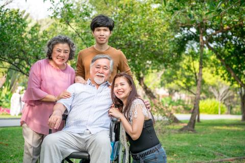 Senior man in a wheelchair with his family in the park