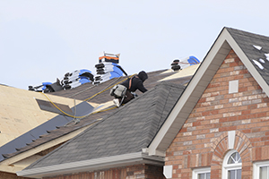 A roofer shingling a roof.